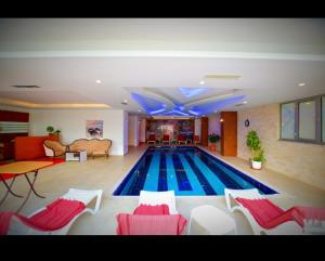 a large swimming pool with red and white chairs in a room at Empire Residence Alanya/Mahmutlar 50m от моря in Alanya