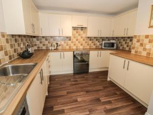 a kitchen with white cabinets and wooden floors and a sink at 2 Wheatsheaf Yard in Morpeth