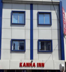 a white building with blue windows and a man in the window at Hotel Kanha Inn in Lucknow