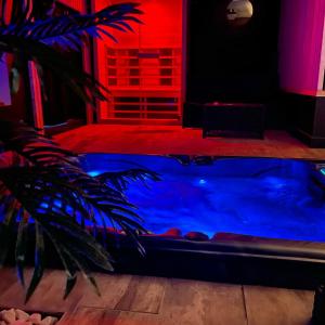 La suite Grenoble spa jacuzzi et sauna privatif في غرونوبل: حوض استحمام ساخن في غرفة مع إضاءة حمراء وزرقاء