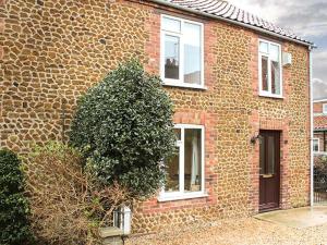 a brick house with a tree in front of it at Driftwood Cottage in Heacham