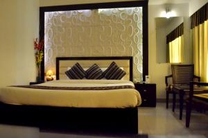 a bedroom with a bed with a large headboard at Hotel Landmark in Gwalior