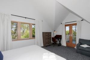 a bedroom with a bed and a chair and windows at Blackfish Bungalow in Wellfleet