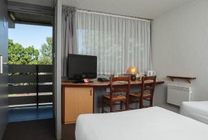 a hotel room with a desk with a television and a bed at Campanile Hotel - Basildon - East of London in Basildon