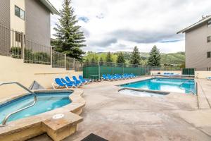 a swimming pool with blue chairs and a building at Beaver Creek West G3 in Beaver Creek