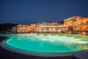 a large swimming pool in front of buildings at night at Cala Cuncheddi - VRetreats in Murta Maria