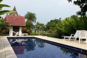 a swimming pool with two chairs and a house at Seabreeze Cottage in Ko Chang