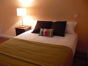 sypialnia z dużym łóżkiem z poduszkami i lampą w obiekcie Casa de Campo Monte Abades w mieście Terras de Bouro