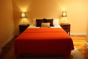 uma grande cama vermelha num quarto com duas lâmpadas em Casa de Campo Monte Abades em Terras de Bouro