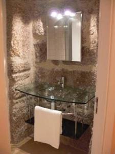 a bathroom with a glass sink and a mirror at Casa de Campo Monte Abades in Terras de Bouro