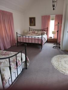 a bedroom with two beds and a window with pink curtains at Old Colony Inn in New Norfolk