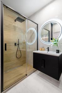a bathroom with a shower with a sink and a mirror at Apartament Baltica Portova Gdynia in Gdynia