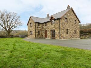 a large stone building with a grass field in front at Ty Berllan in Caersws