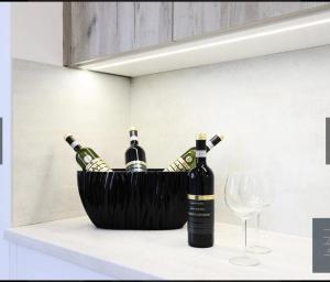 a basket of wine bottles on a counter next to a glass at Dagmar Apartment in Bratislava