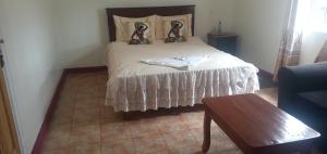 1 dormitorio con 1 cama con colcha blanca en The Crown Place, en Kericho