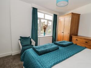 een slaapkamer met een bed met blauwe lakens en een raam bij Manor Heath Apartment 3 in Scarborough