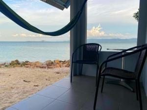 eine Veranda mit 2 Stühlen und einem Tisch am Strand in der Unterkunft Islandlife Bungalows in Thongsala