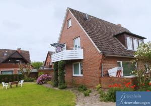 a brick house with a balcony and a yard at Friesenhain Ferienwohnungen in Sankt Peter-Ording
