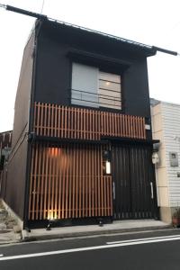 une maison noire avec un portail en bois dans une rue dans l'établissement ゲストハウス扇, à Takamatsu