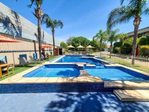 a large swimming pool with blue tiles and palm trees at Sandors Motor Inn in Mildura