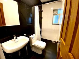 a bathroom with a sink and a toilet and a mirror at Kamat's Hilltop Leisure in Dona Paula