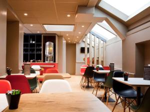 a dining room with tables and chairs and windows at ibis Paris Gare De L'Est TGV in Paris