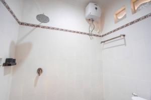 a white bathroom with a shower and a toilet at Adi Guest House in Canggu