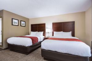um quarto de hotel com duas camas com lençóis brancos e vermelhos em Comfort Inn em Kings Mountain