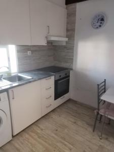 cocina con armarios blancos, fregadero y fogones en Casa da Praia Alfarim, en Sesimbra