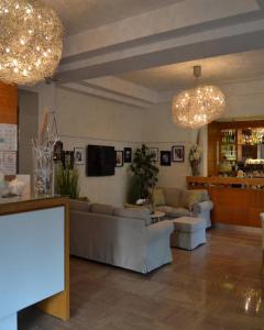 een woonkamer met banken en een tv en kroonluchters bij Hotel Mon Pays in Riccione