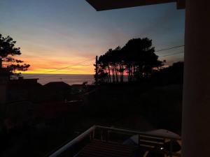 una puesta de sol sobre el océano con árboles en el primer plano en Apartamento Peregrinos Por la Costa Camino Portugués As Casetas, en Rosal