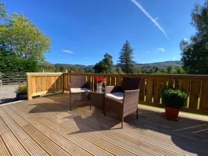 two chairs and a table on a wooden deck at Hill cottage cabins in Fort Augustus