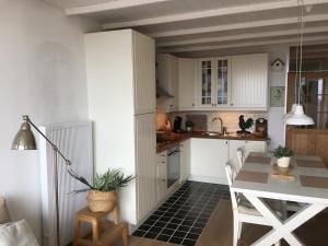 a kitchen with white cabinets and a table and a dining room at Amelotte in Nieuwpoort