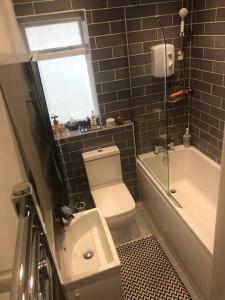 a bathroom with a toilet and a tub and a sink at Lancaster Entire Studio in Brighton & Hove