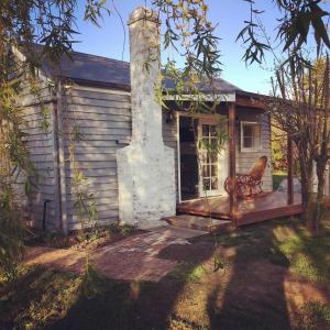 une maison avec une chaise assise sur la terrasse couverte à l'avant dans l'établissement Peg Cottage, à Evandale