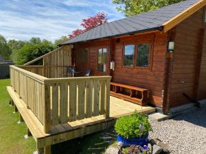 a large wooden cabin with a porch and a deck at Hill cottage cabins in Fort Augustus