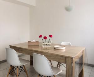 a dining room with a wooden table and white chairs at La Péninsule Town Apartment No 5 in Curepipe