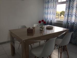 a dining room table with white chairs and a window at La Péninsule Town Apartment No 5 in Curepipe