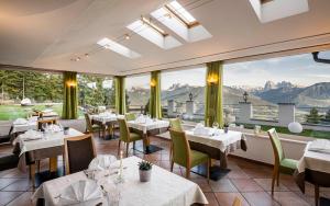 un restaurante con mesas, sillas y ventanas grandes en Granpanorama Wellnesshotel Sambergerhof Superior, en Villandro