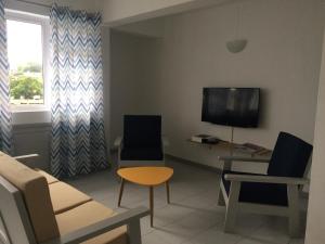 ein Wohnzimmer mit einem Sofa, Stühlen und einem TV in der Unterkunft La Péninsule Town Apartment No 5 in Curepipe