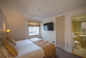 a bedroom with a bed and a bathroom with a television at Royal Victoria Hotel Snowdonia in Llanberis