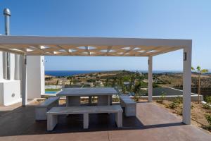 a picnic table on a patio with a view of the ocean at Agia Pelagia Villas in Agia Pelagia