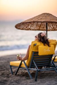 a woman sitting in a beach chair with an umbrella at Sundia Exclusive By Liberty Fethiye Adults Only in Fethiye