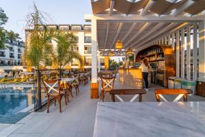 an outdoor patio with tables and chairs and a pool at Sundia Exclusive By Liberty Fethiye Adults Only in Fethiye