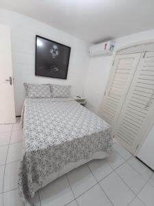 a white bedroom with a bed and a tv at Casa em Condomínio 2 suítes casa 03 in Juazeiro do Norte