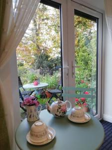 a table with three tea sets on it in front of a window at Rosehips at Kerensa, Naburn in York