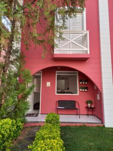 ein rotes Haus mit einer Bank davor in der Unterkunft Casa em Condomínio 2 suítes casa 03 in Juazeiro do Norte