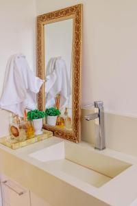 Un lavabo de baño con espejo y un lavabo blanco. en Morada do Estaleiro, en Balneário Camboriú