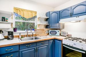 a kitchen with blue cabinets and a sink and a window at Enchanted Cottage in Vashon