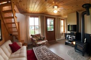 sala de estar con sofá, TV y chimenea en Chalet Paradis de Charlevoix, en Baie-Saint-Paul